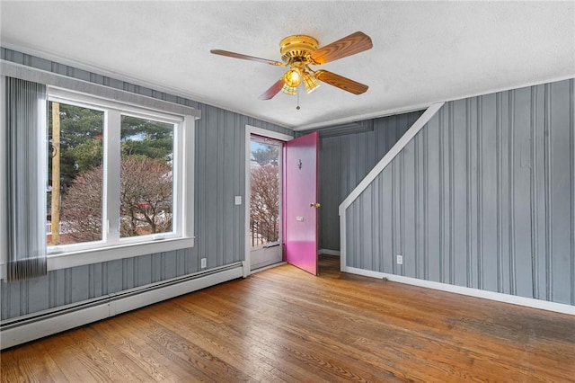 spare room featuring ceiling fan, a baseboard radiator, and wood finished floors