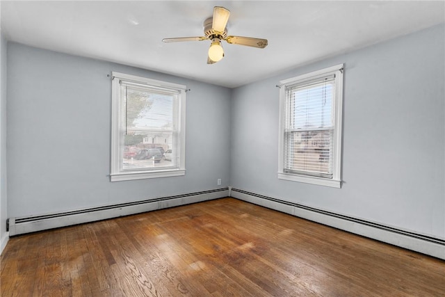 empty room featuring a baseboard heating unit, a wealth of natural light, and hardwood / wood-style floors