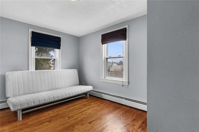 living area featuring plenty of natural light, a baseboard radiator, and wood finished floors