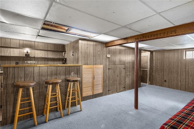 bar with a dry bar, wood walls, carpet flooring, and a paneled ceiling