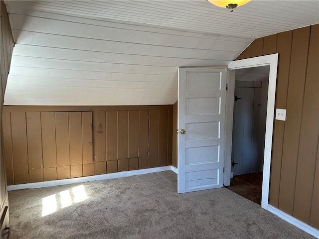 bonus room with carpet floors, wood walls, and vaulted ceiling