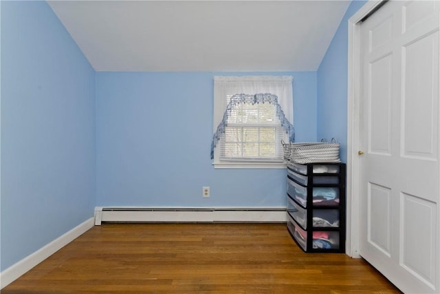 bedroom with a baseboard radiator, baseboards, and wood finished floors