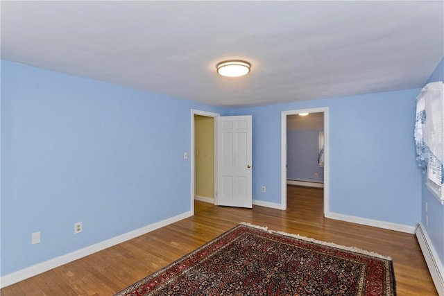 unfurnished bedroom with baseboards, a baseboard radiator, a baseboard heating unit, and wood finished floors