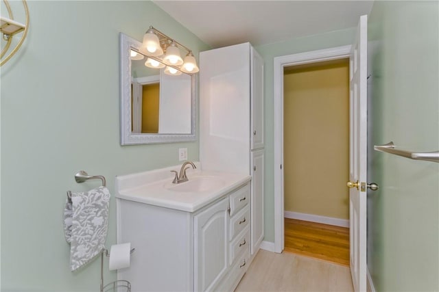 bathroom with baseboards, wood finished floors, and vanity