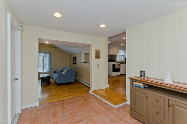 corridor with light tile patterned floors, a baseboard radiator, a sink, and recessed lighting