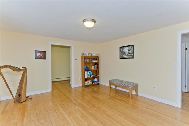 living area with light wood finished floors, a baseboard radiator, and baseboards