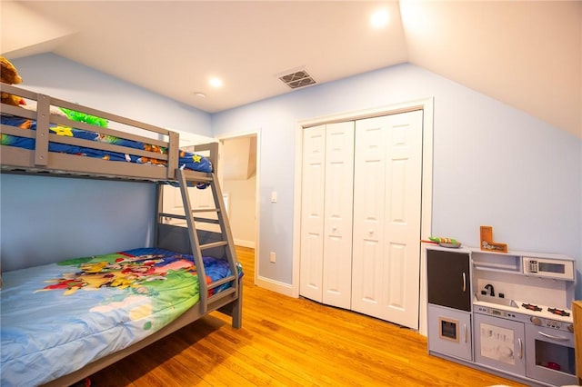 bedroom with vaulted ceiling, baseboards, visible vents, and light wood-style floors