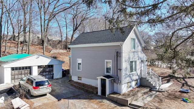 view of side of property with roof with shingles and an outdoor structure