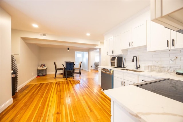 kitchen featuring dishwasher, light countertops, a sink, and decorative backsplash