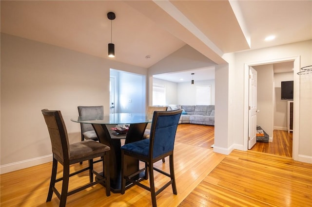 dining area with vaulted ceiling, baseboards, and light wood-style floors