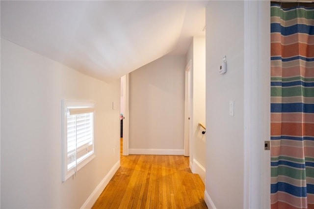 hall with lofted ceiling, baseboards, and wood finished floors