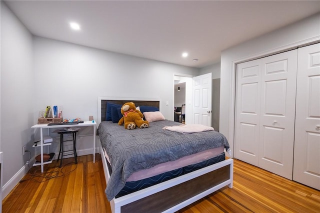 bedroom with a closet, baseboards, wood finished floors, and recessed lighting