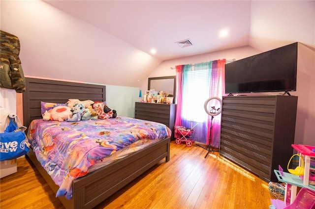 bedroom with visible vents, vaulted ceiling, and hardwood / wood-style floors