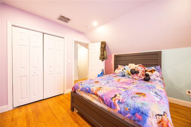 bedroom featuring light wood finished floors, baseboards, visible vents, and vaulted ceiling