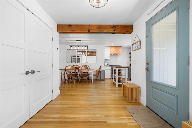 foyer entrance with beam ceiling and light wood-style flooring