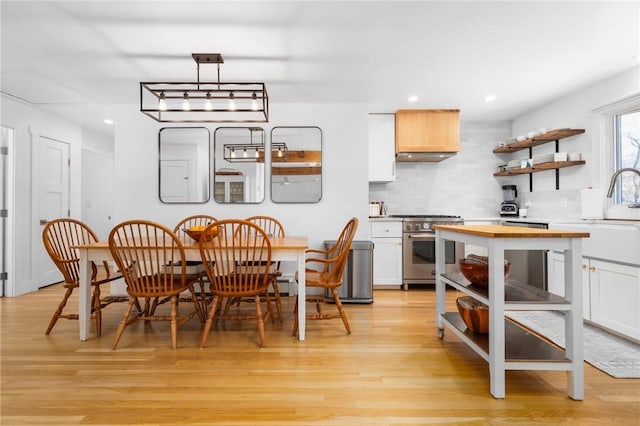 kitchen featuring light wood-type flooring, appliances with stainless steel finishes, wooden counters, and backsplash