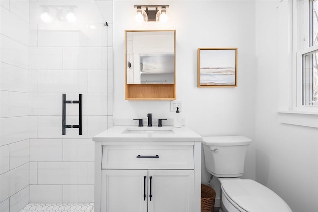 bathroom featuring toilet, a tile shower, and vanity