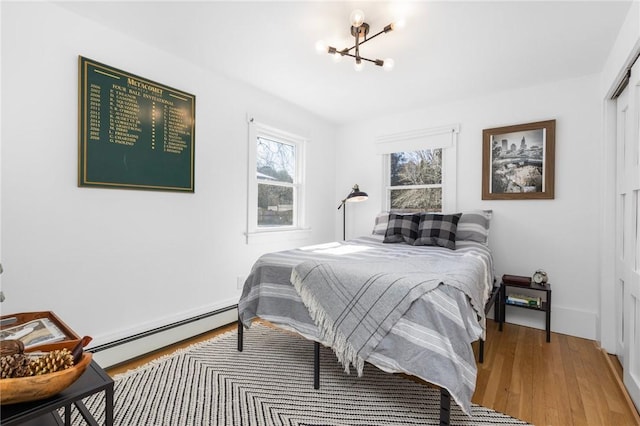 bedroom with a baseboard radiator, a closet, and wood finished floors