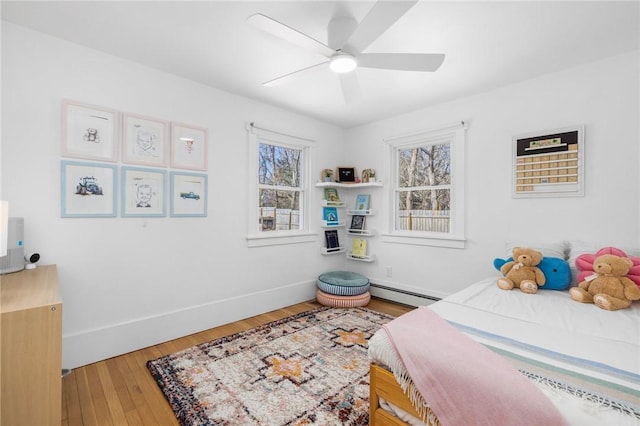 bedroom with baseboards, a baseboard radiator, a ceiling fan, and light wood-style floors