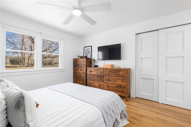 bedroom with light wood-style floors, a closet, and a ceiling fan