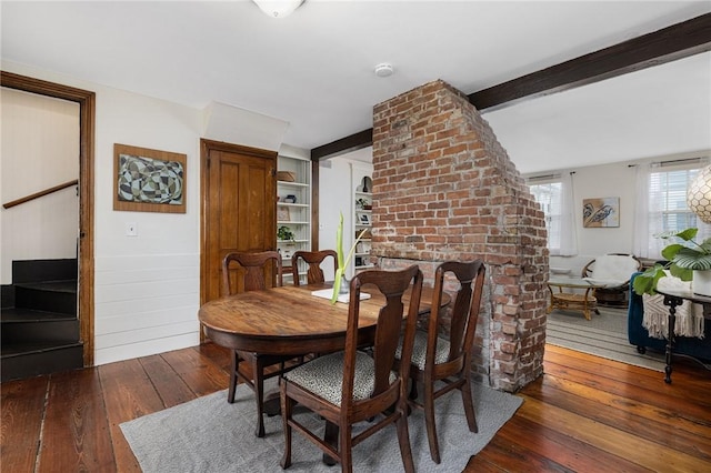 dining room with hardwood / wood-style flooring, built in shelves, and beam ceiling