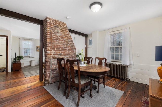 dining area with wood-type flooring, beam ceiling, and radiator