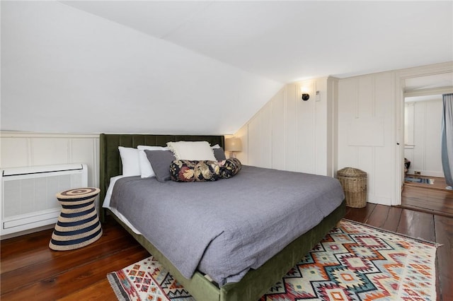 bedroom featuring lofted ceiling, radiator heating unit, and hardwood / wood-style floors