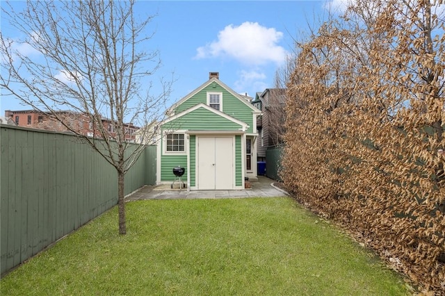 rear view of house with an outbuilding, a fenced backyard, a storage shed, a lawn, and a chimney