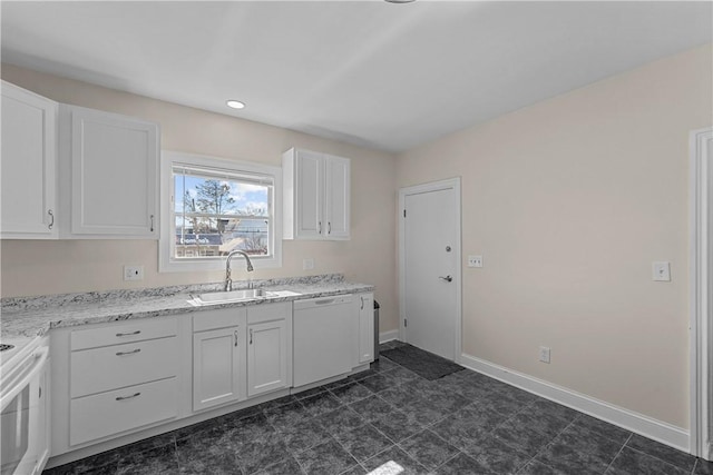 kitchen with light stone counters, white cabinets, a sink, white appliances, and baseboards