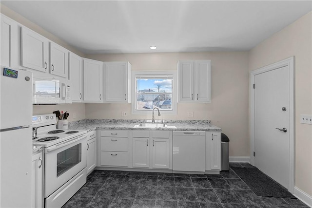 kitchen featuring white appliances, a sink, baseboards, white cabinets, and light stone countertops