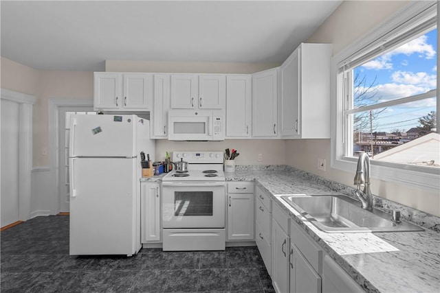 kitchen with white appliances, white cabinetry, and a sink