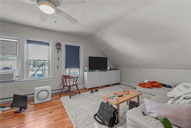 living room with ceiling fan, vaulted ceiling, baseboards, and wood finished floors