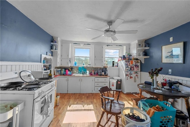 kitchen with a wainscoted wall, white appliances, light wood-style floors, white cabinets, and open shelves