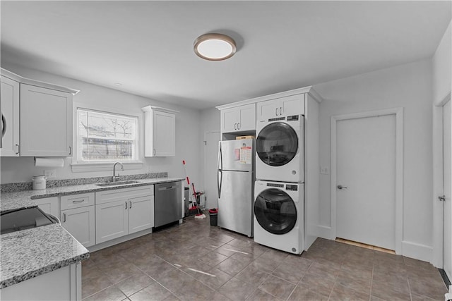 washroom featuring a sink, laundry area, and stacked washer / drying machine