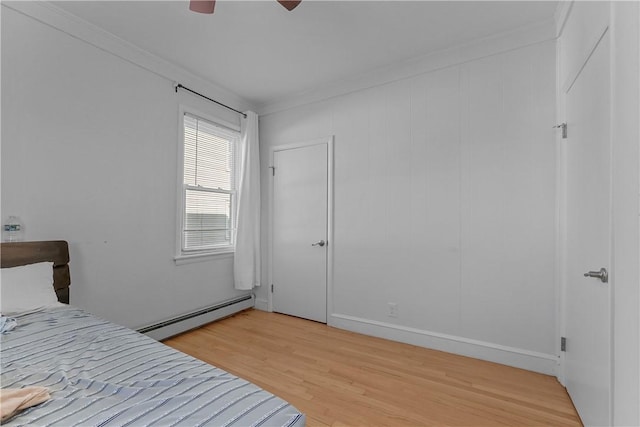 bedroom featuring light wood finished floors, a baseboard radiator, ornamental molding, and ceiling fan