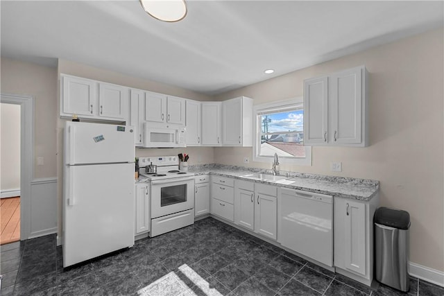 kitchen with white cabinetry, a sink, light stone countertops, white appliances, and baseboards