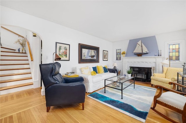 living room featuring light wood-style flooring, arched walkways, and stairway