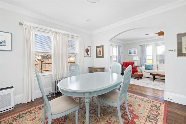 dining area with arched walkways, baseboards, wood finished floors, and crown molding