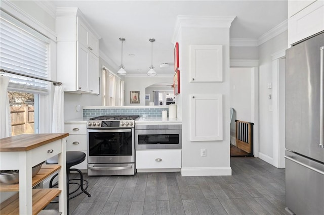 kitchen with white cabinets, backsplash, stainless steel appliances, and crown molding