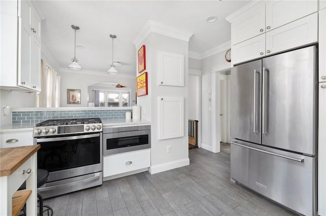 kitchen featuring decorative backsplash, wood counters, stainless steel appliances, crown molding, and white cabinetry