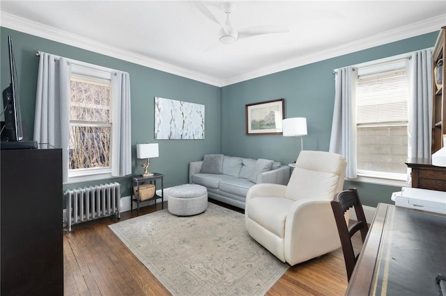 living area with ornamental molding, hardwood / wood-style floors, radiator heating unit, and plenty of natural light