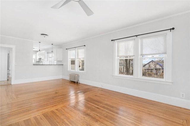 unfurnished living room with light wood finished floors, radiator, ornamental molding, a ceiling fan, and baseboards