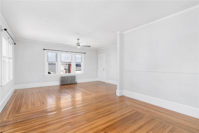 spare room with baseboards, a ceiling fan, radiator, crown molding, and light wood-style floors