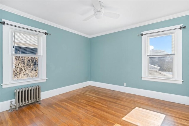 spare room with radiator heating unit, baseboards, crown molding, and wood finished floors