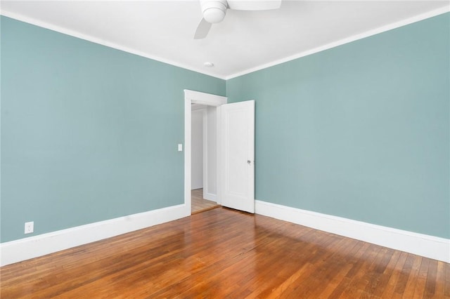 spare room featuring ornamental molding, wood-type flooring, baseboards, and a ceiling fan