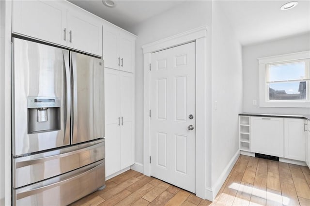 kitchen with stainless steel refrigerator with ice dispenser, recessed lighting, light wood-style flooring, white cabinets, and baseboards