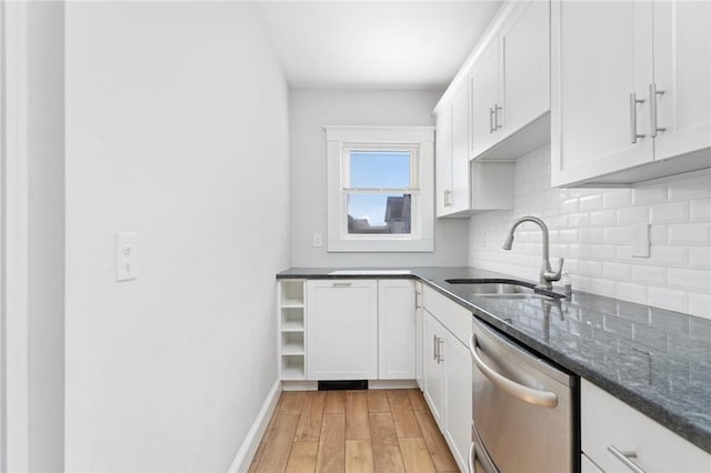 kitchen with light wood finished floors, tasteful backsplash, a sink, white cabinetry, and stainless steel dishwasher