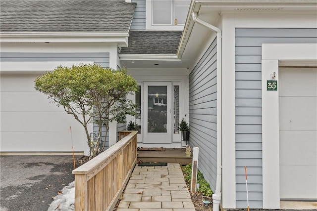 property entrance featuring a garage and a shingled roof