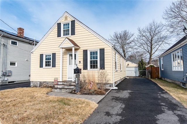 view of front of house featuring driveway, fence, and a front lawn