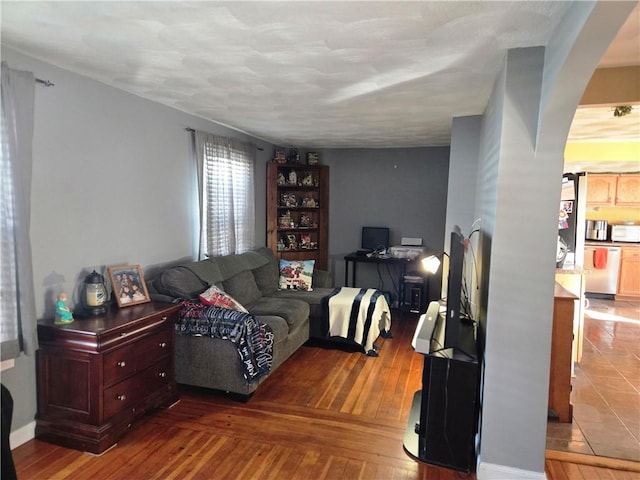 living room with arched walkways and hardwood / wood-style floors